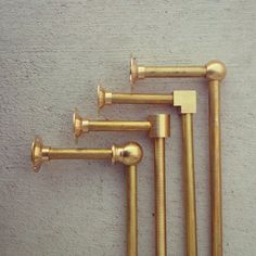 four brass pipes are lined up against the wall