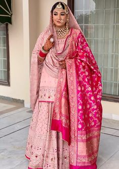 a woman wearing a pink and gold bridal outfit