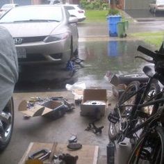 a bunch of bikes that are sitting on the ground in front of a car and some boxes