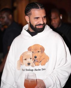 a man wearing a white hoodie with a dog on it and holding a drink