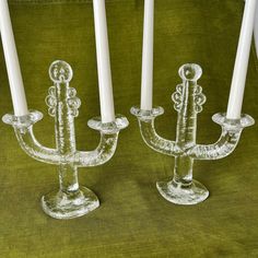 two glass candlesticks sitting next to each other on a green cloth covered table