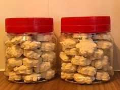 two jars filled with marshmallows sitting on top of a wooden floor