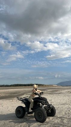 a man riding on the back of an atv in the middle of nowhere, under a cloudy blue sky