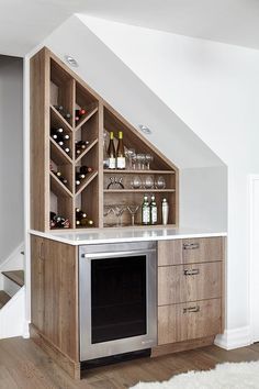 a wine rack in the corner of a kitchen under a slanted ceiling with stairs leading up to it