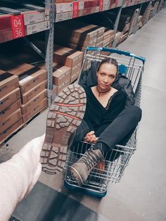 a woman sitting in a shopping cart next to a shoe