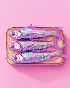 three little fish are sitting on top of a piece of bread with pink icing