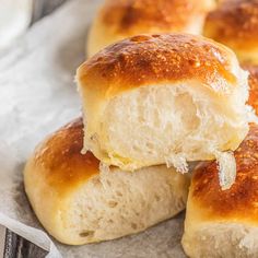 closeup of bread rolls with butter on them sitting on a piece of parchment paper