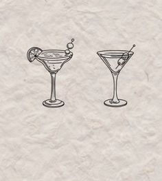 two martini glasses with an olive garnish on the rim and one filled with liquid