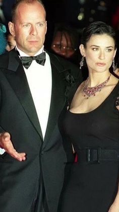 a man in a tuxedo standing next to a woman wearing a black dress