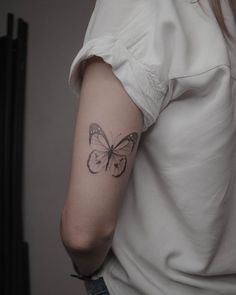 a woman's arm with a butterfly tattoo on the left side of her arm