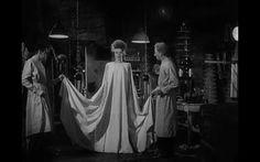 three women in aprons and capes standing around