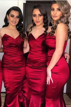 three women in red dresses standing next to each other with their hands on their hips