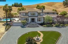 this is an aerial view of a large home in the hills with a pool and fountain