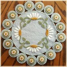 a white and green doily with flowers in the center on a wooden table top