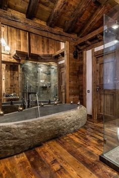 a large stone bathtub sitting inside of a bathroom next to a wooden floor and walls