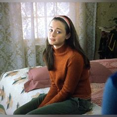 a woman sitting on top of a bed next to a window