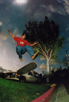 a skateboarder is doing a trick in the air near a car and tree