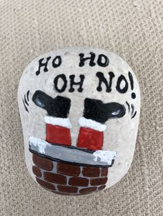 a painted rock that says, ho hoo oh no with santa's boots on it