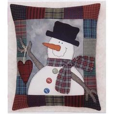 a snowman with a hat and scarf on it's head is sitting in front of a plaid pillow