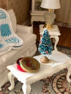 a small christmas tree sitting on top of a white table in a living room next to a couch