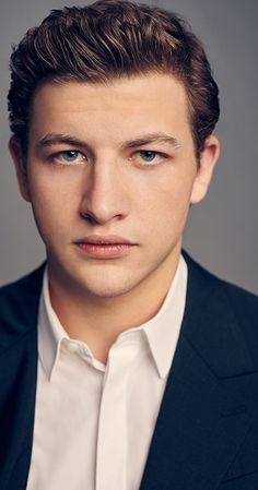 a man in a suit and white shirt is looking at the camera with an intense look on his face