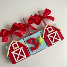 an ornament made to look like a barn with red ribbon and numbers on it