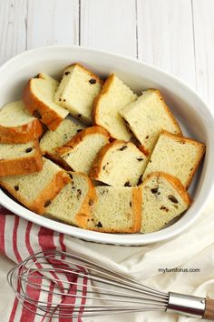 a white bowl filled with slices of bread next to a whisk on a red and white towel