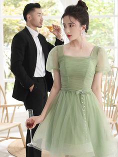 a woman in a green dress standing next to a man