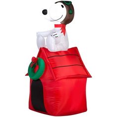 a large inflatable dog sitting on top of a red house with a green wreath