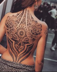 the back of a woman's body with tattoos on it