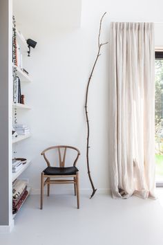 a chair sitting in front of a window next to a book shelf