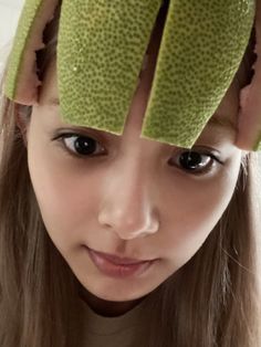 a young woman with long hair has two pieces of fruit on her head and is looking at the camera