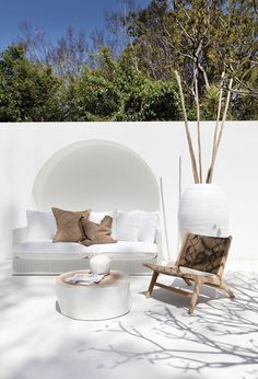 a white couch sitting next to a chair and table on top of a cement floor