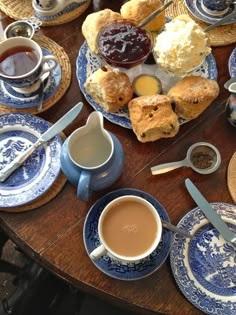 a table topped with blue and white plates filled with pastries next to cups of coffee