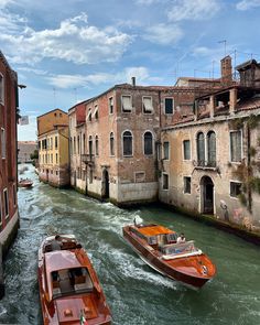 two boats traveling down a river next to tall buildings