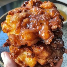 a person holding up a piece of food in front of a plate with sauce on it