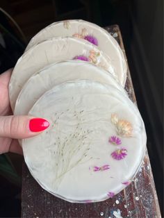 a woman's hand holding three plates with flowers on them