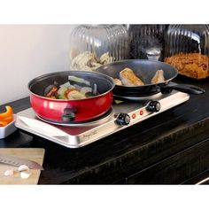 two pans on top of a stove with food cooking in them next to each other