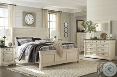 a bedroom with white furniture and a large clock on the wall above the headboard