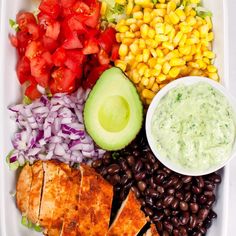 a tray filled with chicken, beans, corn, avocado, and tomatoes