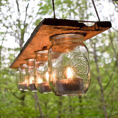 mason jars filled with candles hanging from a wooden beam