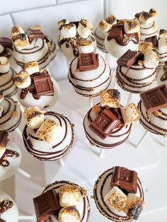 many desserts are arranged in rows on a white platter with chocolate and marshmallows