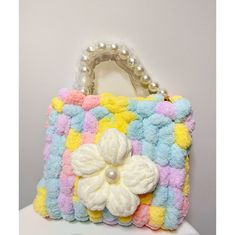 a handbag with a flower on the front and pearls hanging from it's handle