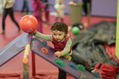 a small child playing on a slide in a play area with other children and toys