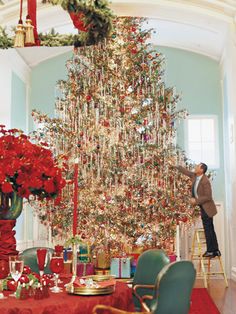 a large christmas tree is in the middle of a room with red and green decorations