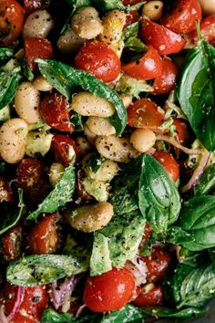 a salad with tomatoes, spinach and chickpeas is shown in a bowl