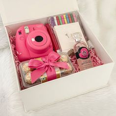 a pink camera sitting in a white box filled with confection and candys