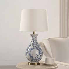 a blue and white vase sitting on top of a table next to a lamp