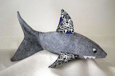 a stuffed shark is sitting on a white sheet with black and white designs in it's mouth