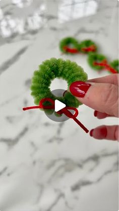 a person is holding a fake christmas wreath with red and green pom - poms